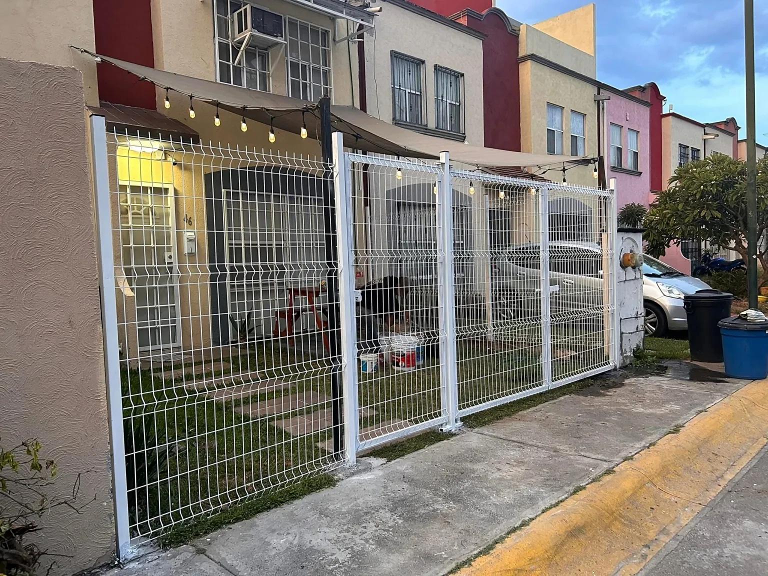 Cerco metálico blanco fabricado e instalado frente a una vivienda